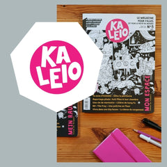 Magazin mit dem Titel Kaleio liegt auf dem Tisch, daneben Stift und Notizbuch. 